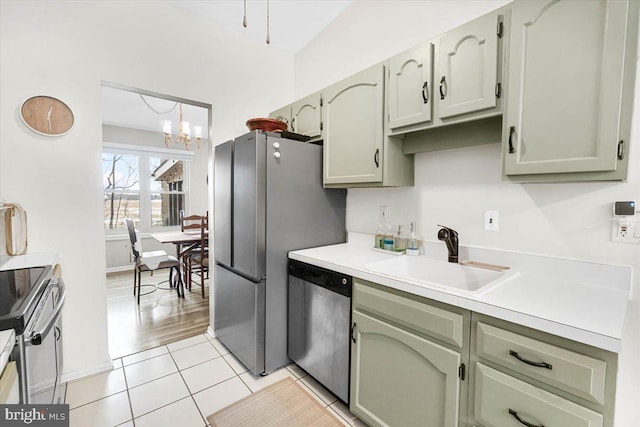 kitchen with light tile patterned floors, appliances with stainless steel finishes, green cabinetry, a chandelier, and sink