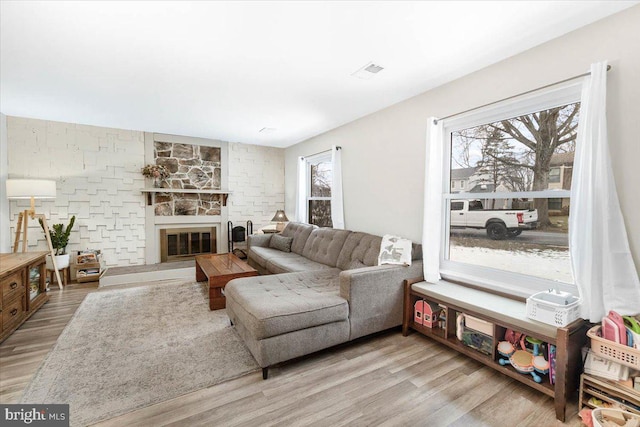 living room with a stone fireplace and light hardwood / wood-style floors