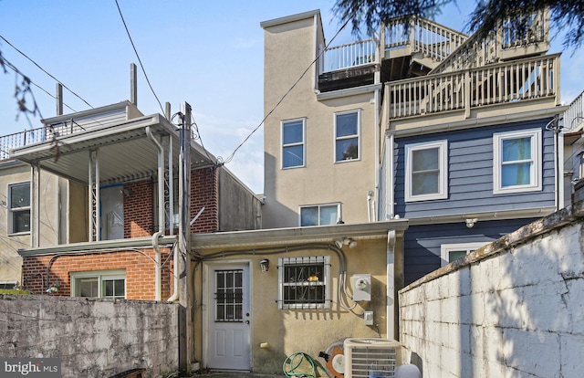 rear view of property with stucco siding, central AC, and fence