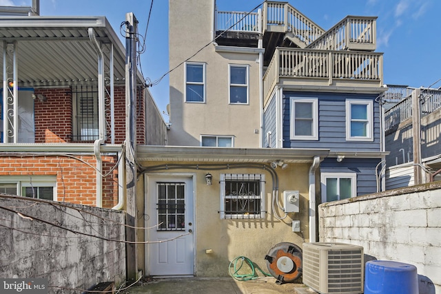 rear view of house featuring stucco siding, central AC, and fence