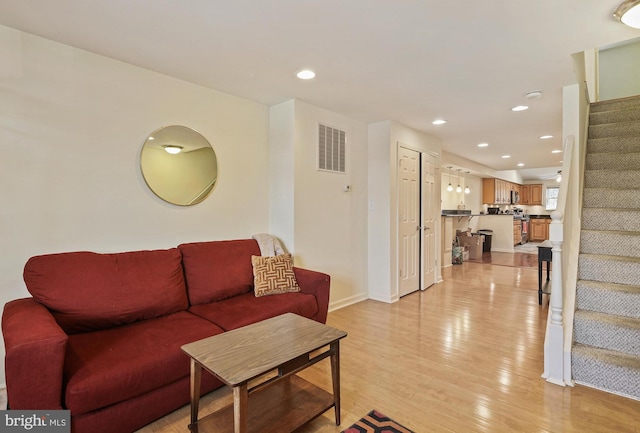 living room with visible vents, baseboards, stairway, light wood-type flooring, and recessed lighting