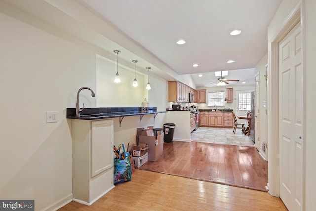 kitchen featuring dark countertops, recessed lighting, light wood-style floors, and a sink