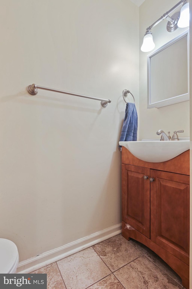 half bath featuring vanity, tile patterned floors, toilet, and baseboards