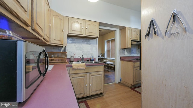 kitchen with tasteful backsplash, sink, and light hardwood / wood-style flooring