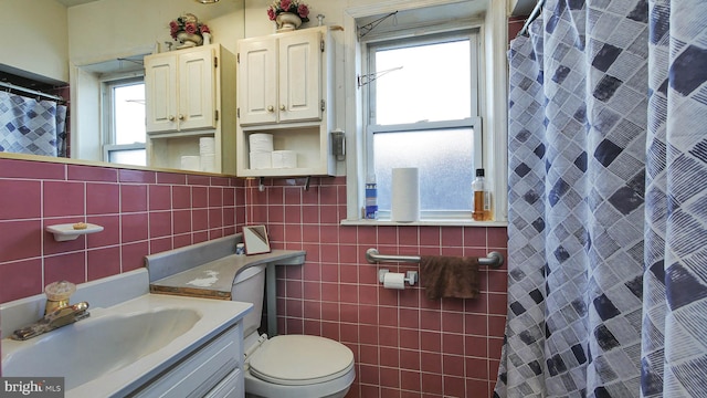 bathroom with curtained shower, tile walls, toilet, and vanity