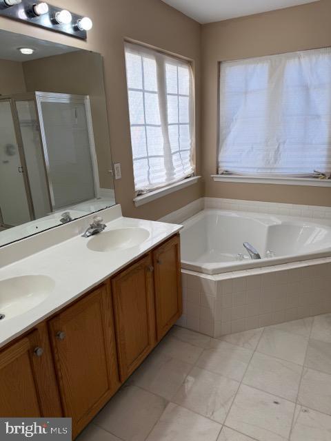 bathroom with tile patterned flooring, shower with separate bathtub, and vanity