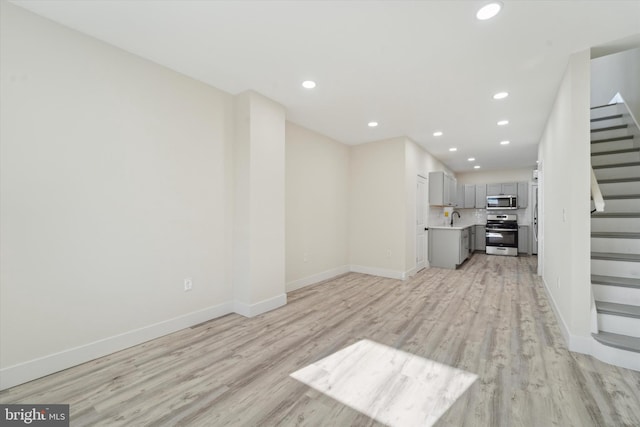 unfurnished living room with sink and light wood-type flooring