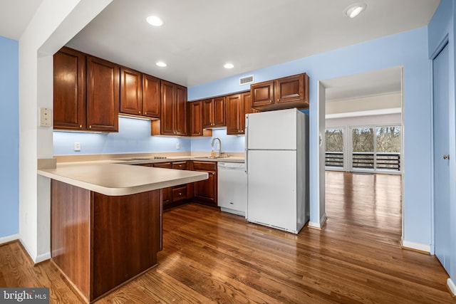 kitchen featuring kitchen peninsula, dark hardwood / wood-style flooring, white appliances, and sink