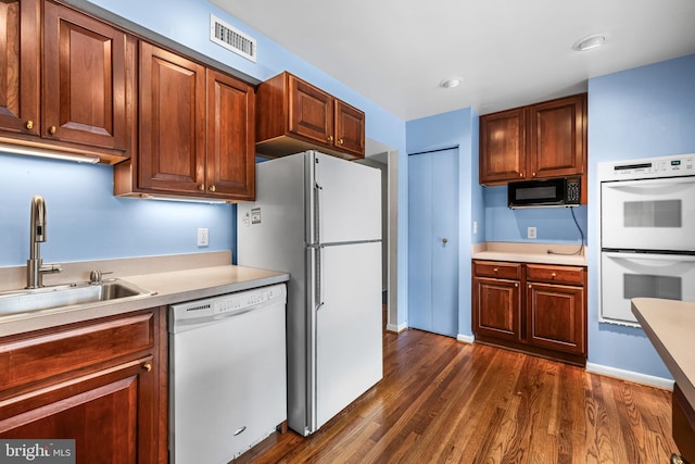 kitchen with white appliances, dark wood-type flooring, and sink