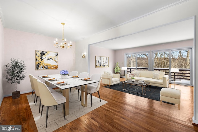 dining room featuring ornamental molding, wood-type flooring, and an inviting chandelier