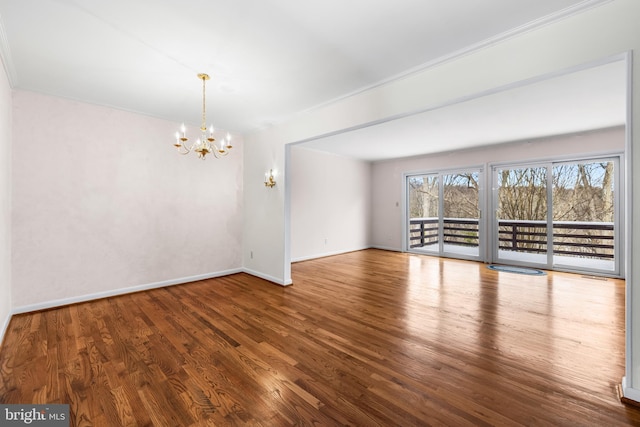 spare room with hardwood / wood-style flooring, an inviting chandelier, and crown molding