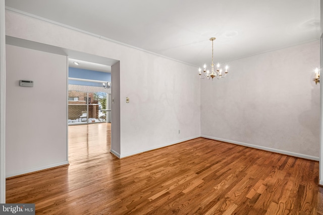 spare room featuring ornamental molding, hardwood / wood-style flooring, and a notable chandelier