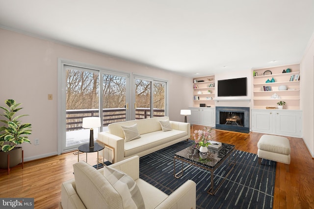 living room featuring built in shelves and light hardwood / wood-style floors