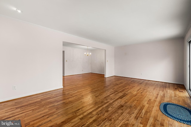 unfurnished room with a chandelier and hardwood / wood-style flooring