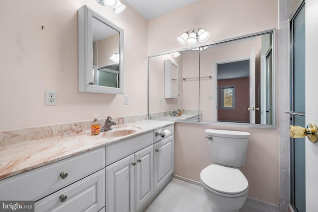 bathroom with vanity, a shower with shower door, and toilet