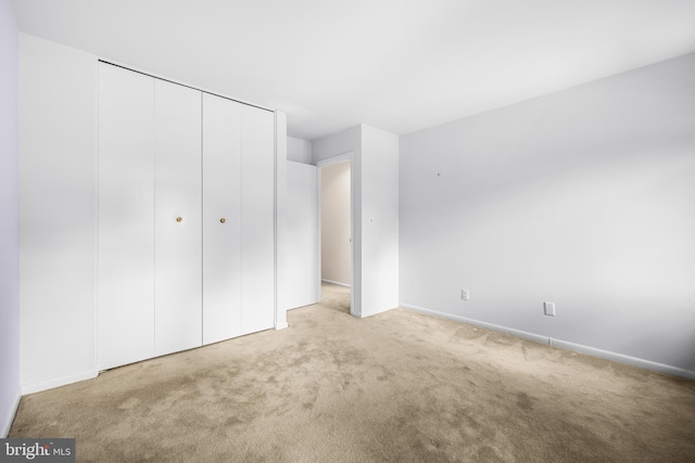 unfurnished bedroom with a closet and light colored carpet