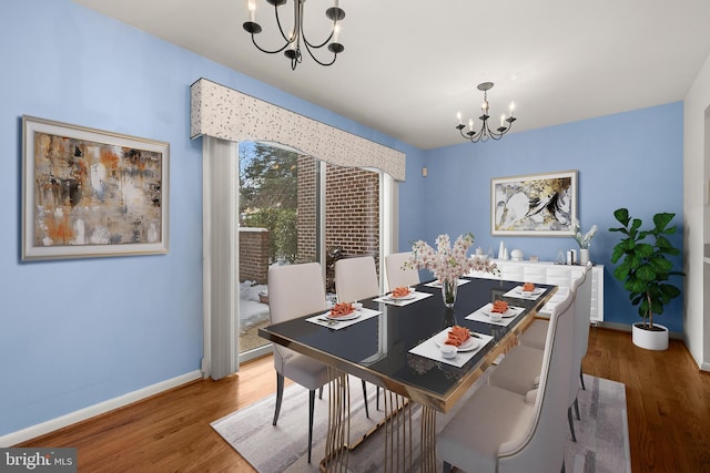 dining space with wood-type flooring and an inviting chandelier