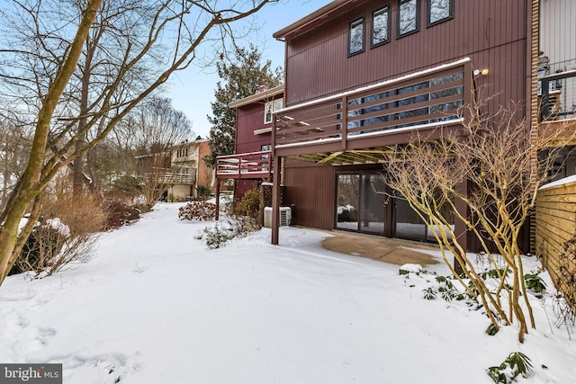 snow covered property featuring central air condition unit and a wooden deck