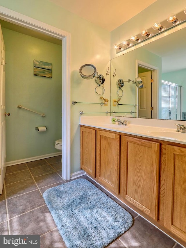 bathroom with toilet, vanity, and tile patterned floors