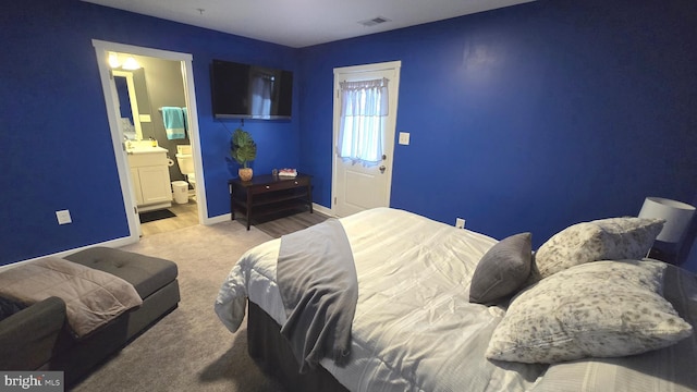 bedroom with ensuite bathroom and light colored carpet