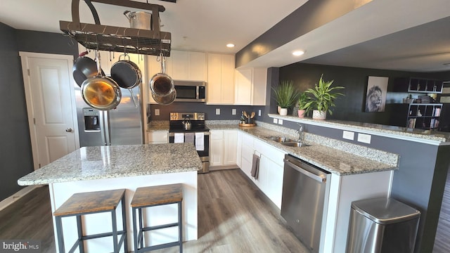 kitchen with sink, a kitchen island, dark hardwood / wood-style floors, white cabinets, and appliances with stainless steel finishes