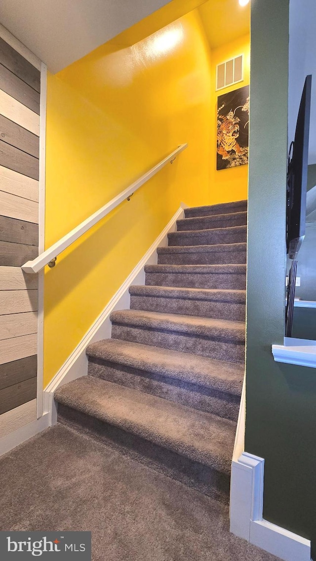 staircase featuring wooden walls