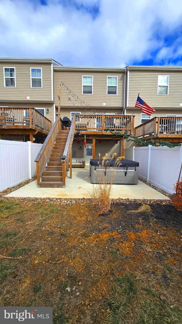 back of property with a wooden deck and a patio