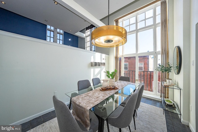 dining space with a high ceiling and dark tile patterned flooring