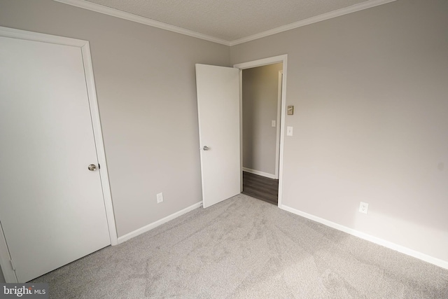 unfurnished bedroom featuring light colored carpet, a textured ceiling, and ornamental molding