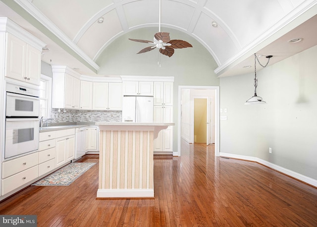 kitchen with tasteful backsplash, white appliances, vaulted ceiling, white cabinetry, and a kitchen island