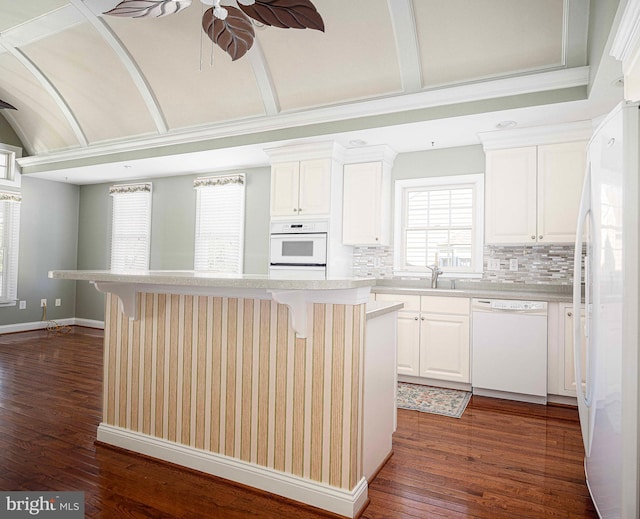 kitchen featuring a kitchen breakfast bar, tasteful backsplash, white appliances, a kitchen island, and white cabinetry