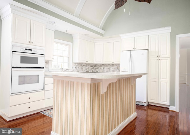 kitchen featuring white cabinets, a center island, white appliances, and a breakfast bar area