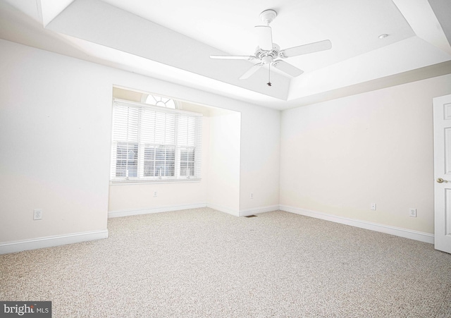 carpeted spare room featuring ceiling fan and a raised ceiling