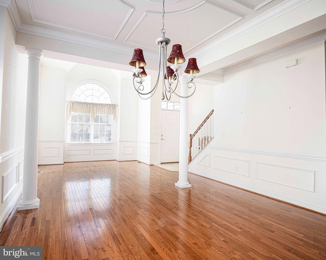 interior space featuring coffered ceiling, hardwood / wood-style flooring, a chandelier, ornamental molding, and decorative columns