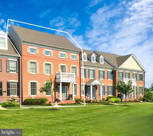 view of property featuring a balcony and a front yard