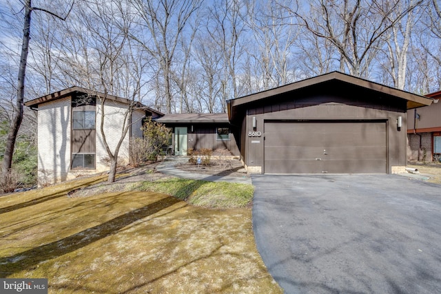 view of front of home featuring aphalt driveway, brick siding, and a garage