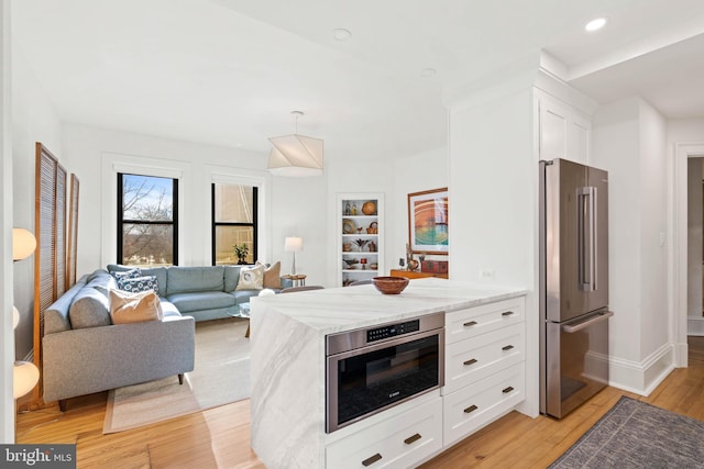 kitchen featuring light stone countertops, stainless steel appliances, decorative light fixtures, light hardwood / wood-style flooring, and white cabinetry