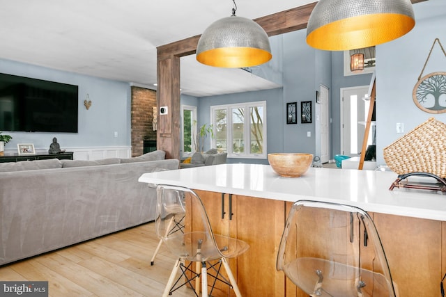 kitchen featuring light wood-type flooring, pendant lighting, a fireplace, and a kitchen bar