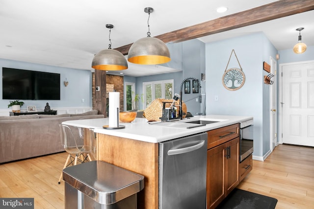 kitchen featuring sink, pendant lighting, light wood-type flooring, and an island with sink