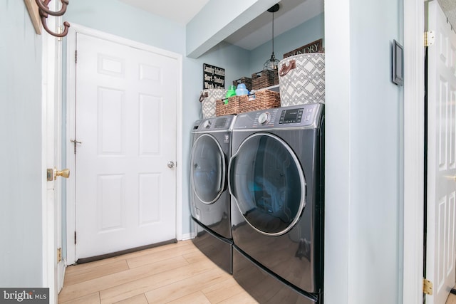 laundry room with light wood-type flooring and washing machine and clothes dryer