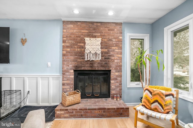 living room with a brick fireplace, a wealth of natural light, and light hardwood / wood-style flooring