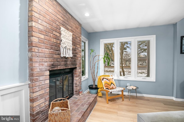 living area featuring a brick fireplace and light hardwood / wood-style flooring