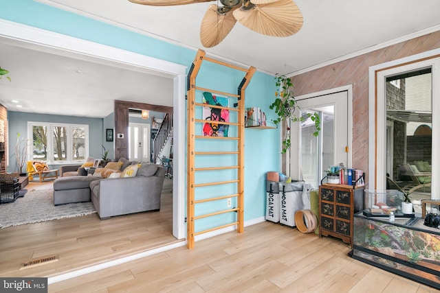 interior space featuring light wood-type flooring, ceiling fan, and wood walls