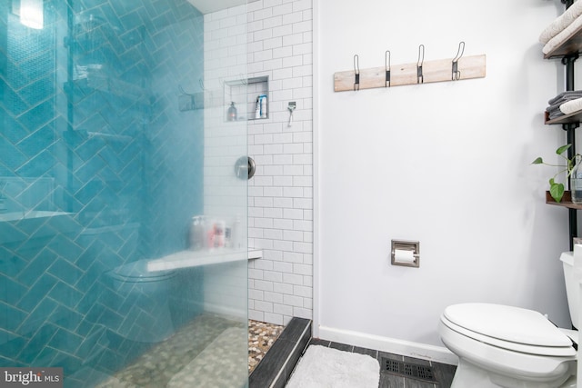 bathroom with hardwood / wood-style flooring, toilet, and a tile shower