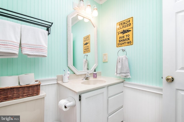 bathroom with toilet, wood walls, and vanity