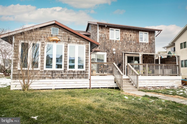 rear view of property featuring a wooden deck and a lawn