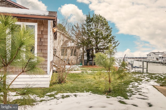 yard layered in snow featuring a water view and a dock