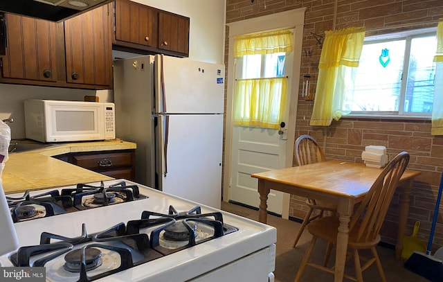 kitchen with brick wall and white appliances