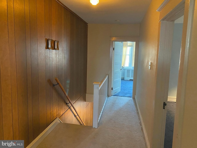 hallway with light colored carpet and wooden walls