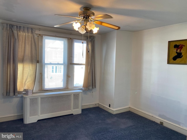 unfurnished room featuring dark colored carpet, plenty of natural light, ceiling fan, and radiator